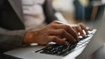 Close-up of black businesswoman working on laptop.