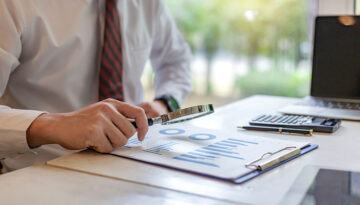 Businessman holding a magnifying glass with graph information do