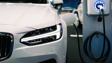 The Inflation Reduction Act: Electric Vehicle Credits White electric car plugged into a charging station.