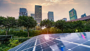 The Inflation Reduction Act: Energy Efficiency Credits and Provisions Solar panels laid out on the ground with trees and cityscape in the background