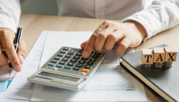 Income Tax Deductions vs. Tax Credits… Which One Is Better? Tax professional determining tax deductions and tax credits with calculator on tax Form 1040